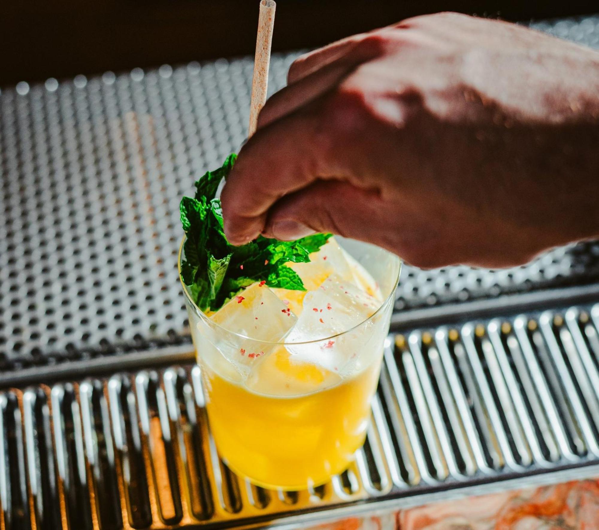 Vignette Collection Yours Truly Dc By Ihg Washington Kültér fotó A bartender garnishes a cocktail with mint.